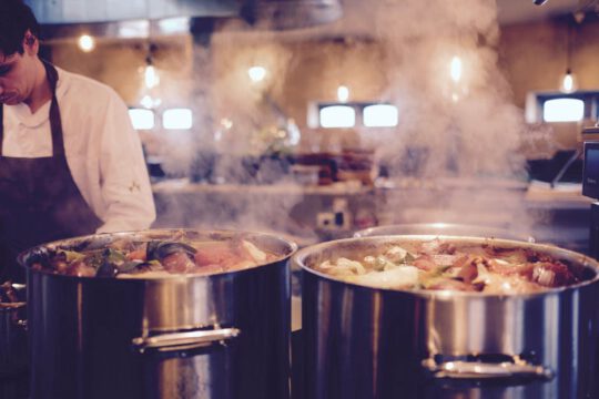 Chef with large cooking pots in restaurant kitchen | SLM Facilities