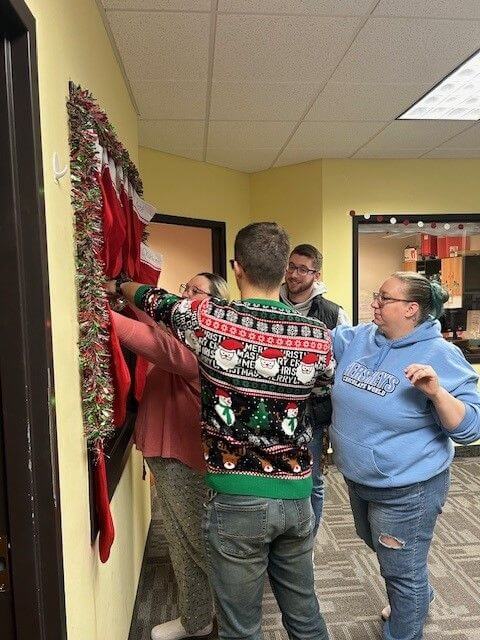 a group of employees in festive ware decorating for the holidays